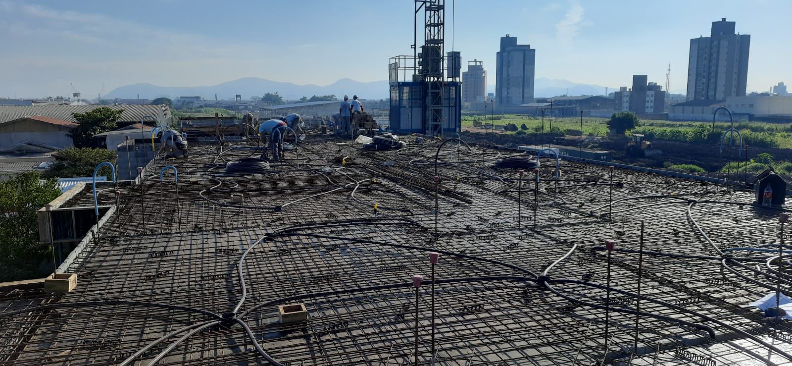 Armadura de laje pronta para concretagem em obra de grande porte, com grua ao fundo